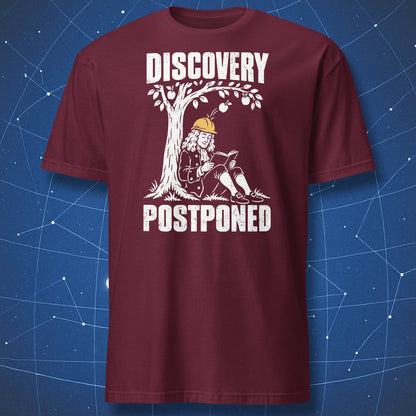 Maroon Discovery Postponed T-shirt with a white Newton cartoon, an apple tree, and a yellow hard hat.