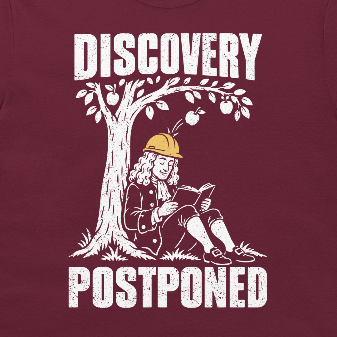 Close-up of Newton reading as an apple bounces off his yellow helmet, with white Discovery Postponed text on maroon fabric.