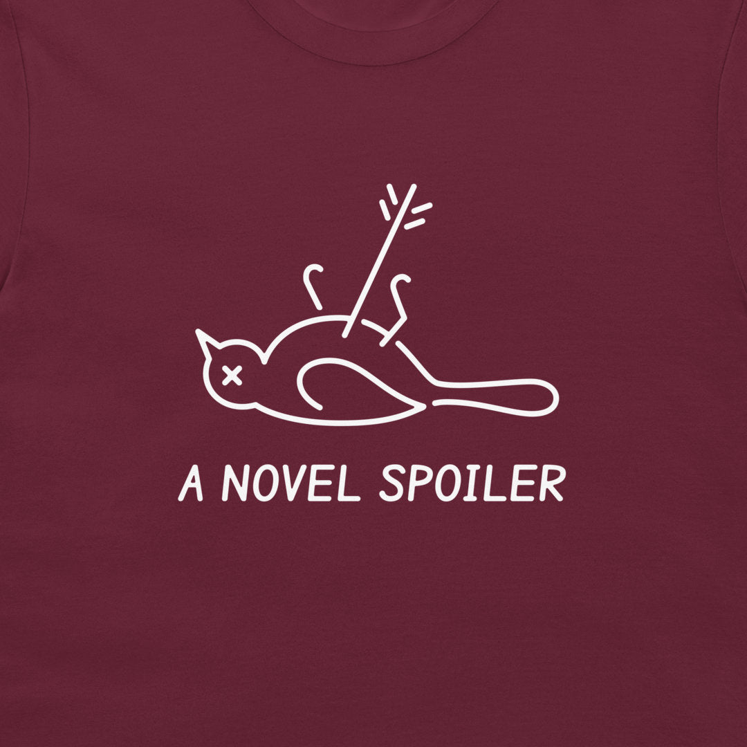 Close-up of the white dead mockingbird graphic and “A NOVEL SPOILER” caption on a maroon T-shirt.